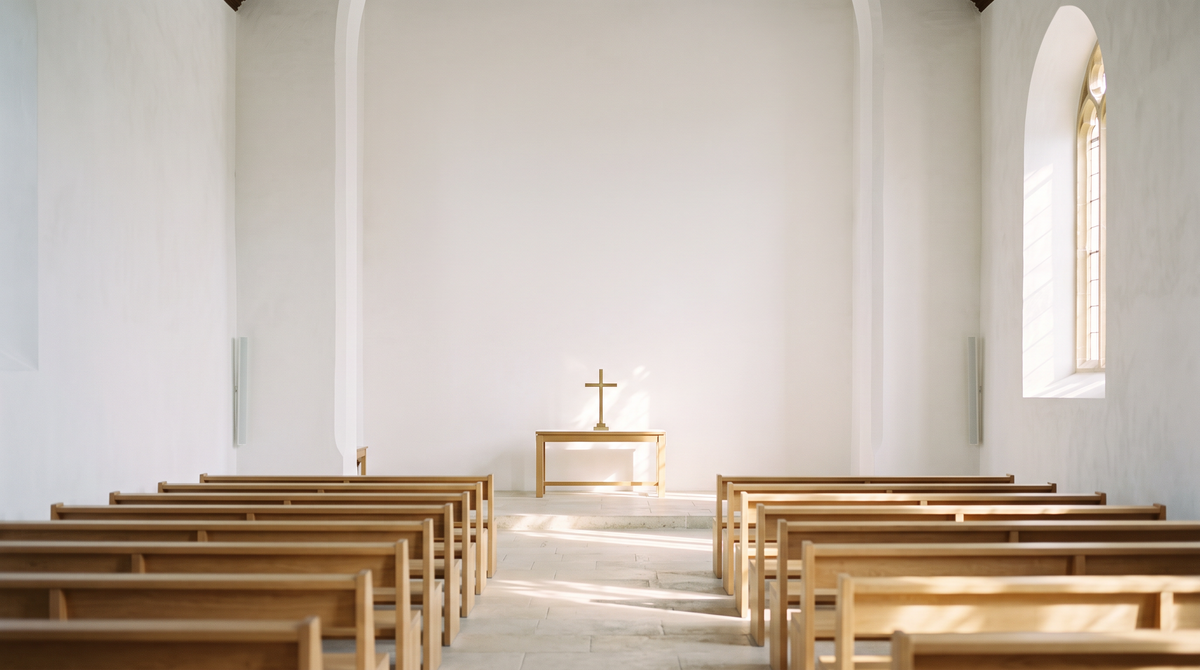 Sunlit minimalist church interior with arched window and wooden pews